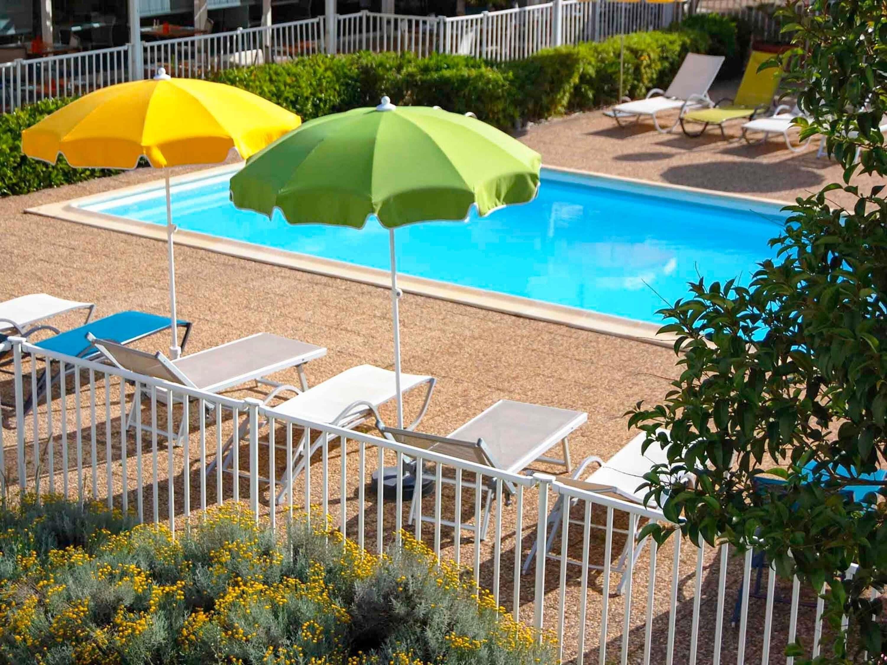 A swimming pool with sun umbrellas and lounge chairs.