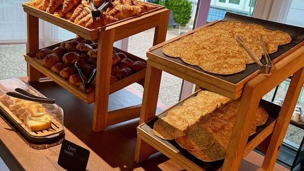 Mostrador de panadería con cruasanes, un pastel y un letrero que anuncia una oferta de pasteles.