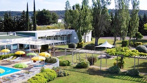 Un hotel con piscina, tumbonas y un patio cubierto.