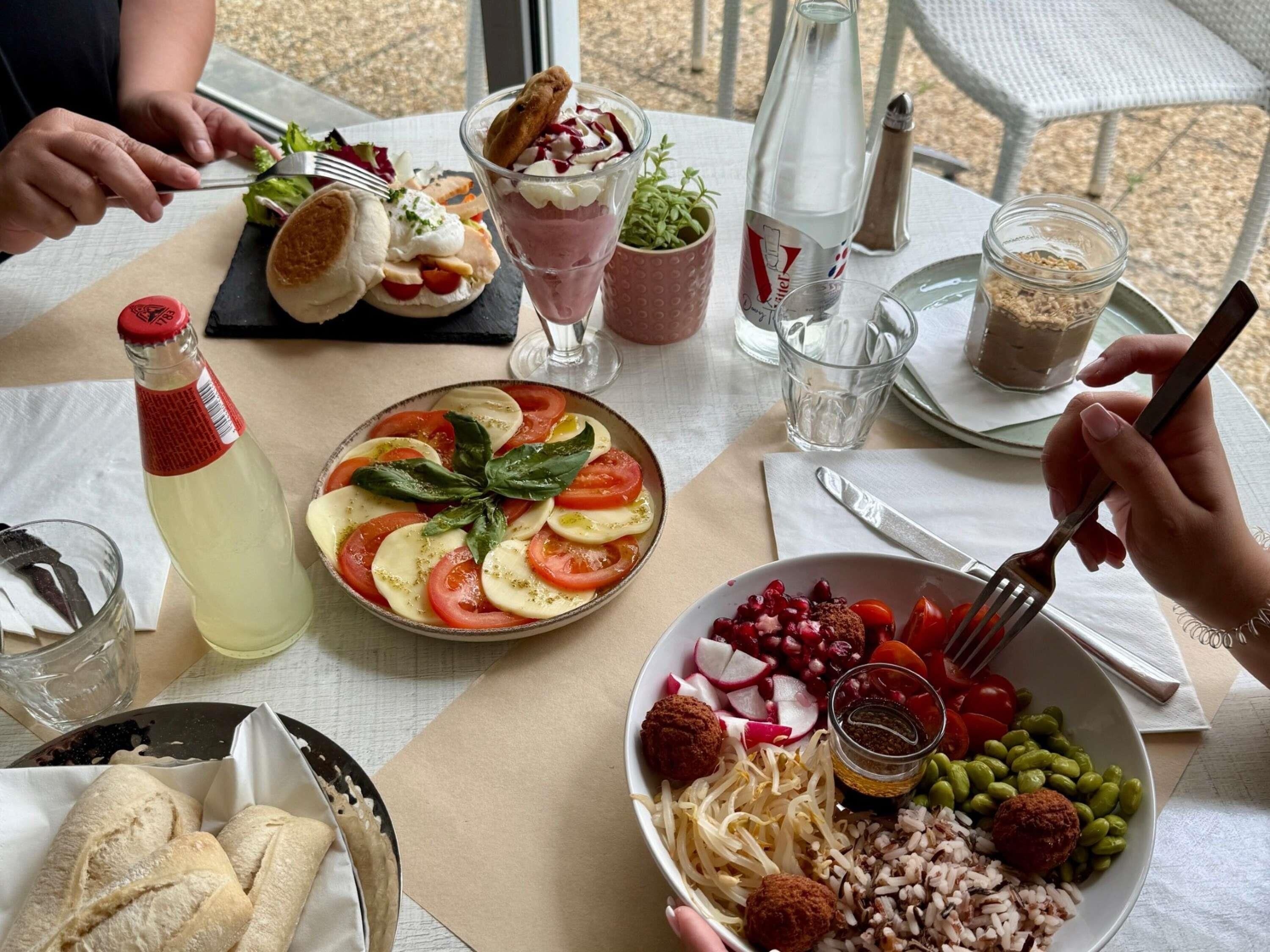 A table set with various dishes, including a salad with tomatoes and basil, a bowl of rice with vegetables, and a plate of bread.