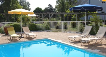 Una piscina al aire libre de temporada, sombrillas