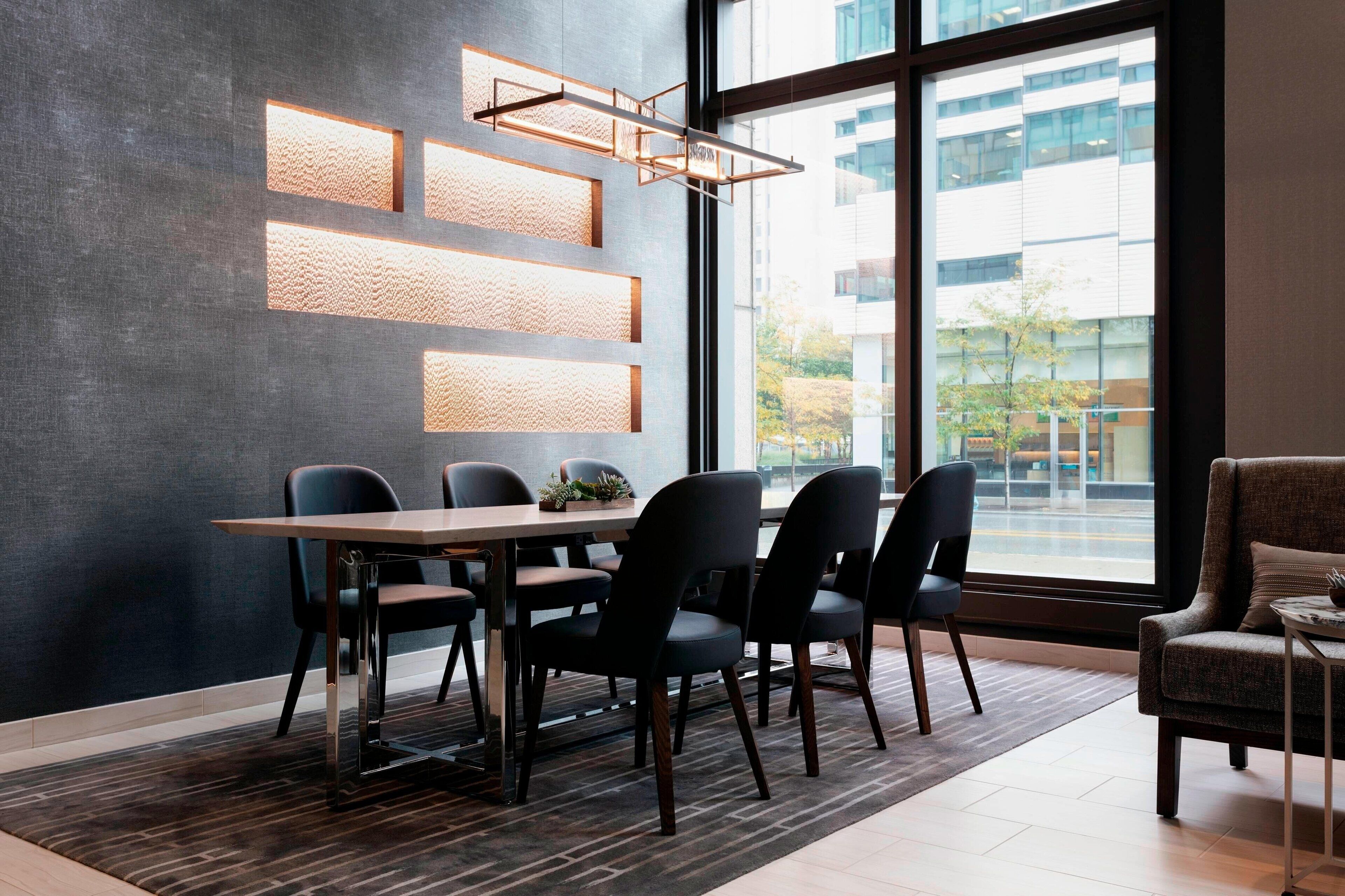 A modern dining area with a large table, six chairs, and a unique wall-mounted light fixture.