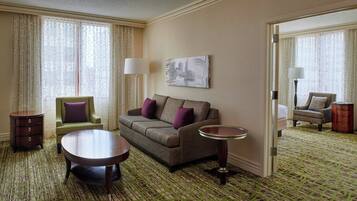 A hotel room with a sofa, armchair, side table, and a mirror.