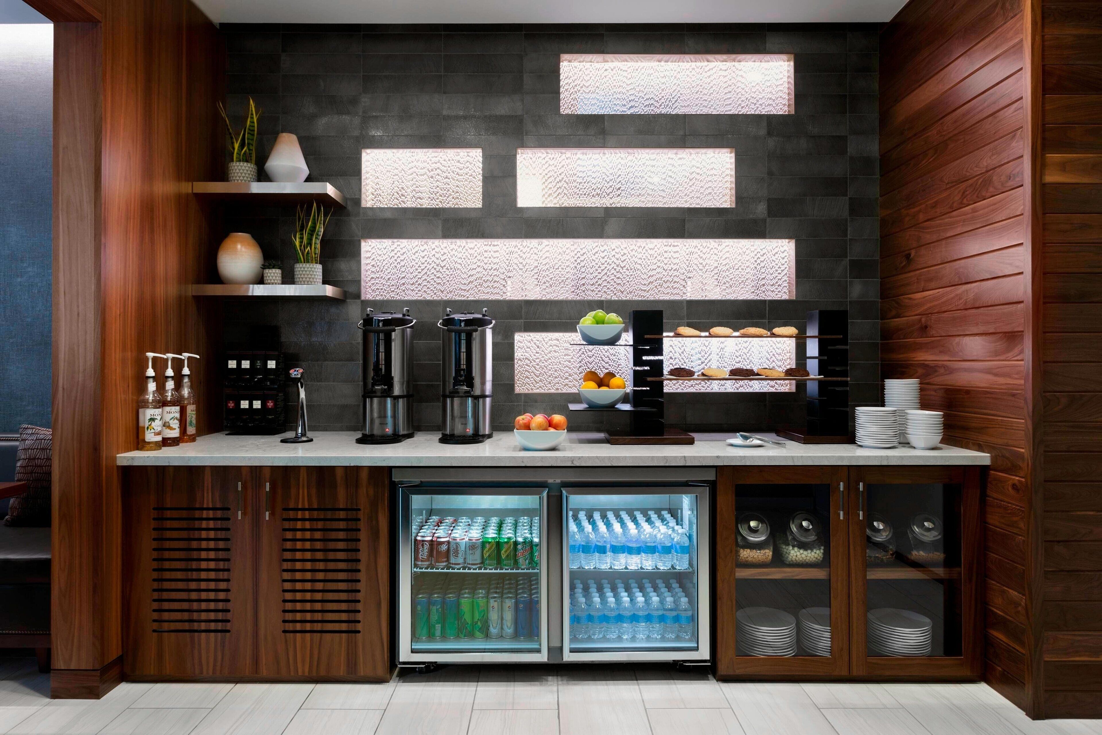 A kitchenette with a built-in coffee maker, tea maker, and a mini-fridge stocked with beverages.
