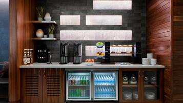 A kitchenette with a built-in coffee maker, tea maker, and a mini-fridge stocked with beverages.