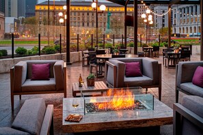 An outdoor seating area with fire pits, tables, and chairs, overlooking a cityscape. - Cleveland Marriott Downtown at Key Tower (Cleveland)