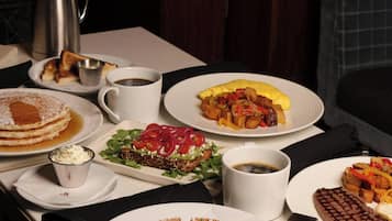 A breakfast table with various dishes including pancakes, waffles, toast, and a waffle with strawberries.