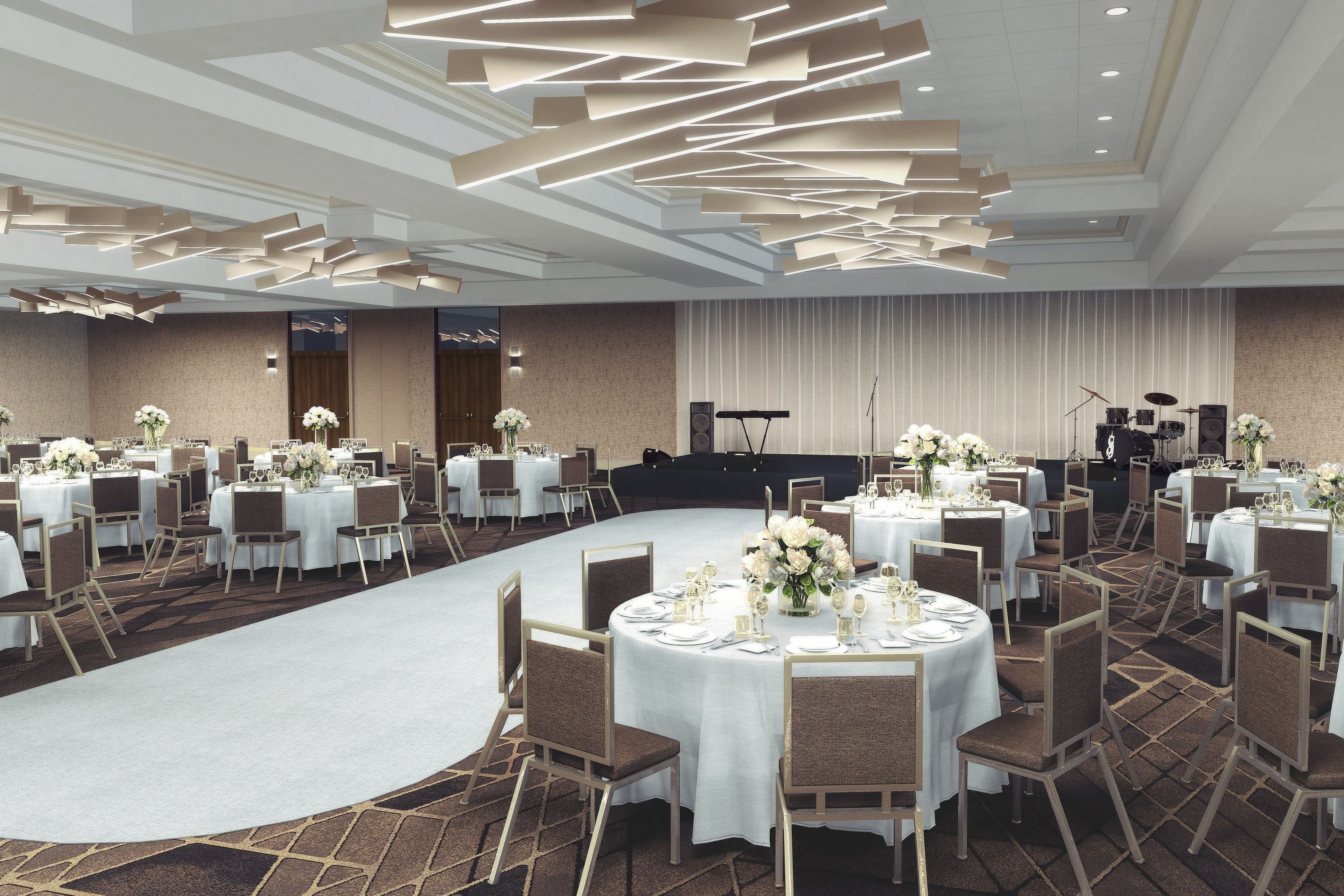 A banquet hall with round tables set for dining, a stage with musical instruments, and a carpeted floor.