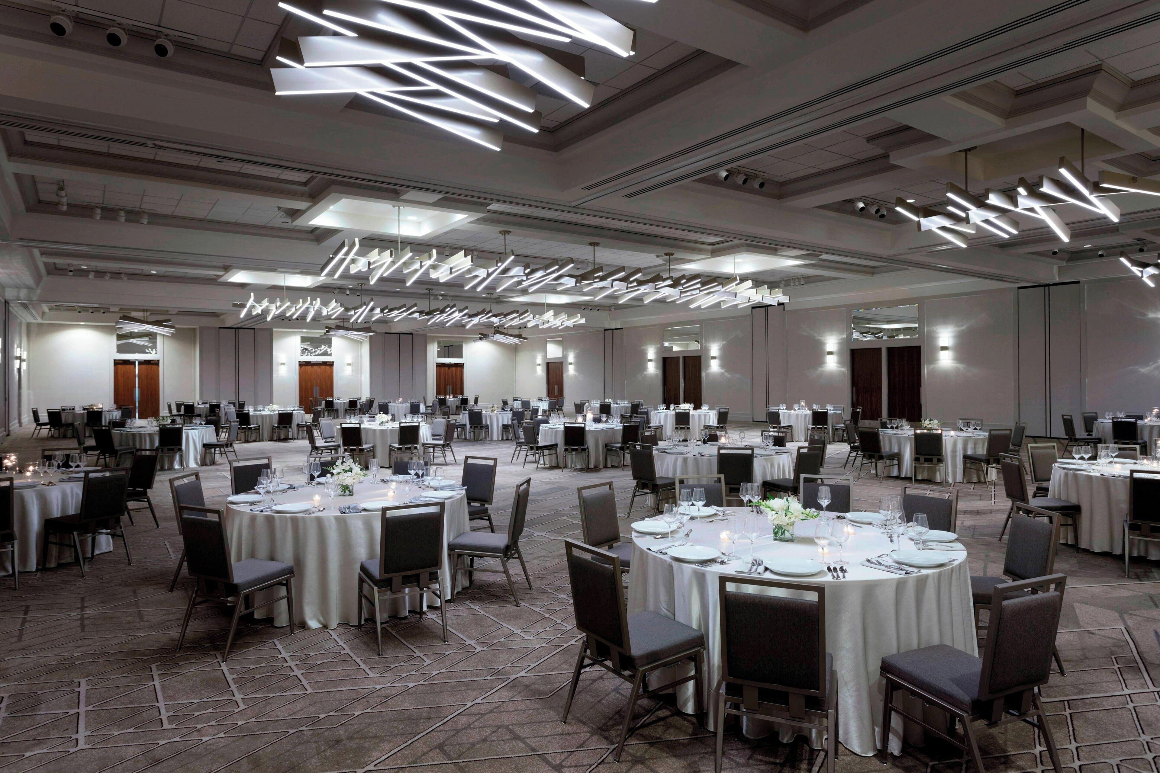 A large banquet hall with round tables set for dining, equipped with chairs and table settings.