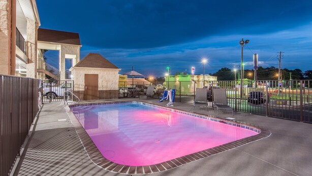 A swimming pool with a tiled edge, a covered seating area, and a fenced patio. - Econo Lodge Jasper (Jasper)