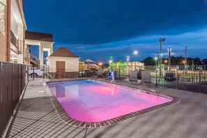 A swimming pool with a tiled edge, a covered seating area, and a fenced patio. - Econo Lodge Jasper (Jasper)