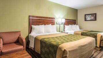 A hotel room with two beds, a sofa, a nightstand, and a wall-mounted lamp.