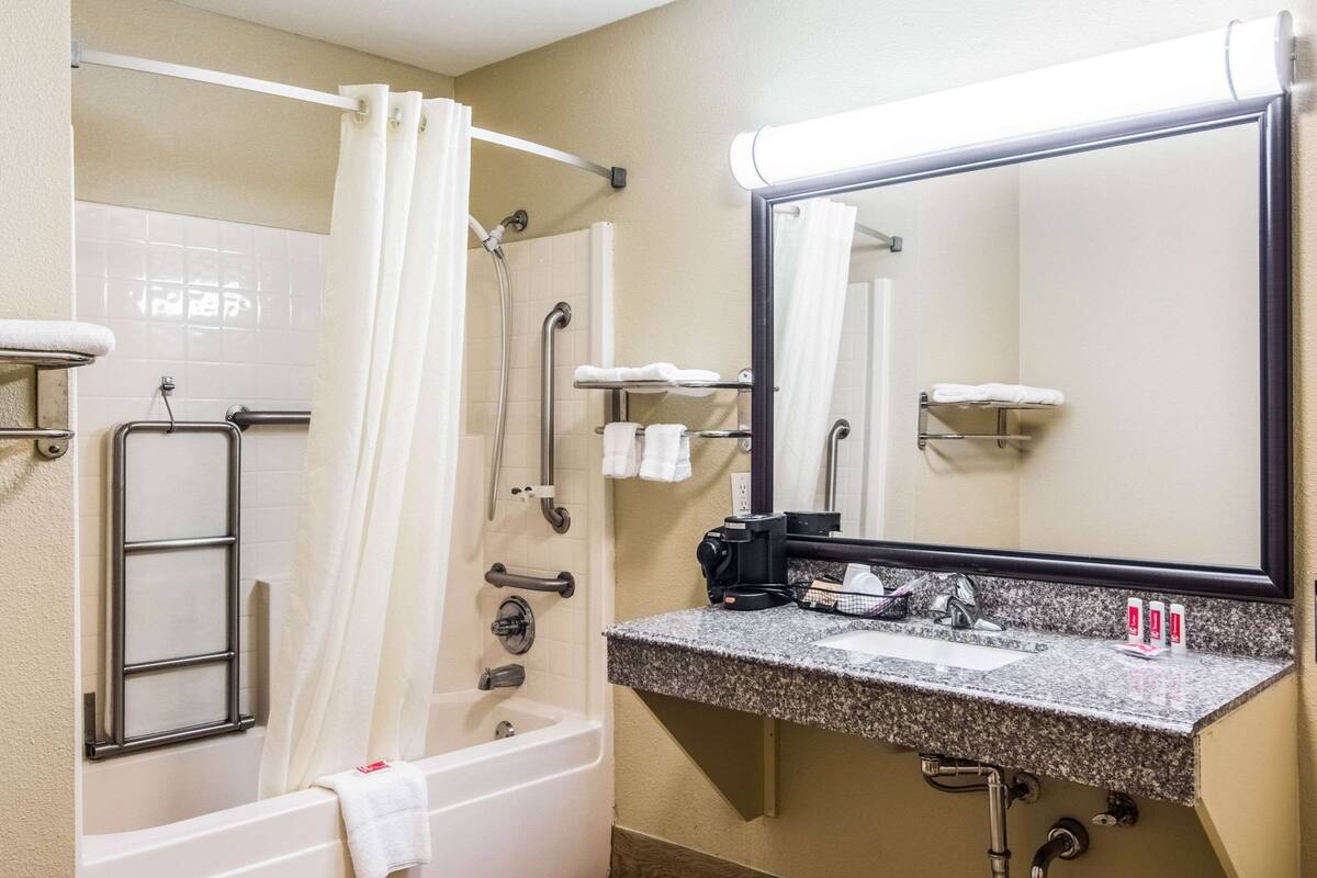 Un baño con bañera, ducha y lavamanos con espejo.
