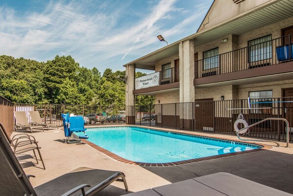A swimming pool with lounge chairs and a lifeguard stand, surrounded by a fence. - Econo Lodge Jasper (Jasper)