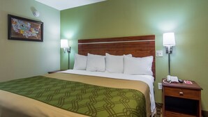 A hotel room with a bed, green walls, a framed map, and a nightstand with a phone. - Econo Lodge Jasper (Jasper)