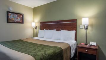 A hotel room with a large bed, two bedside tables with lamps, a wall clock, and a framed map on the wall.