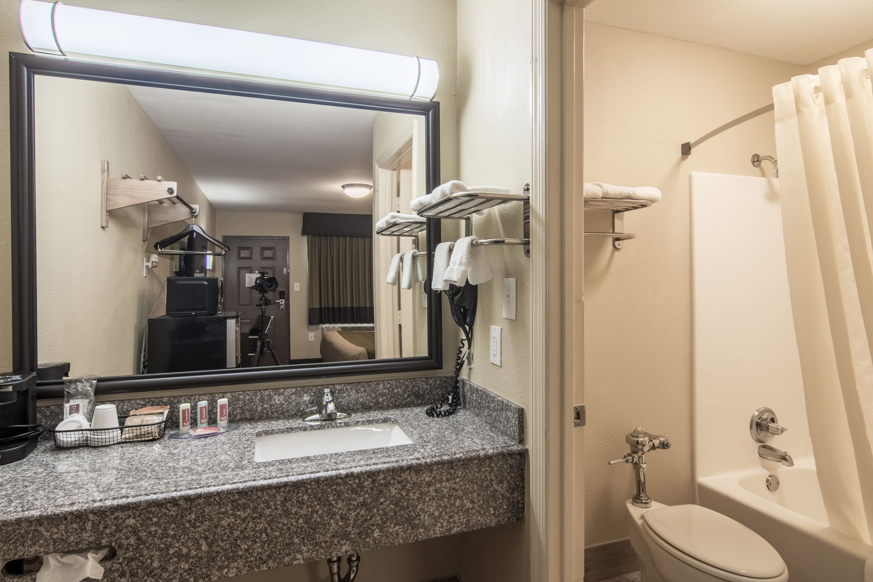 A bathroom with a sink, mirror, towel rack, and bathtub.
