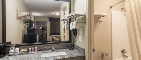 A bathroom with a sink, mirror, towel rack, and bathtub.