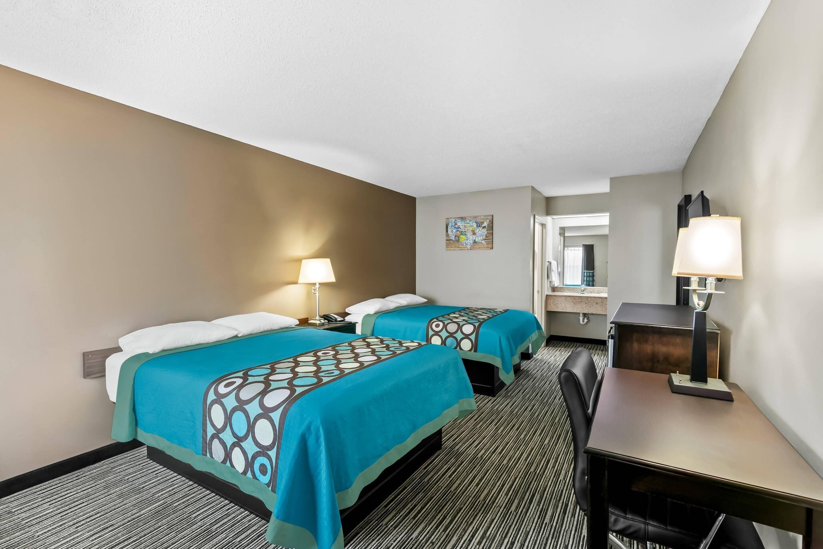 Une chambre d’hôtel avec deux lits, un bureau et une chaise.