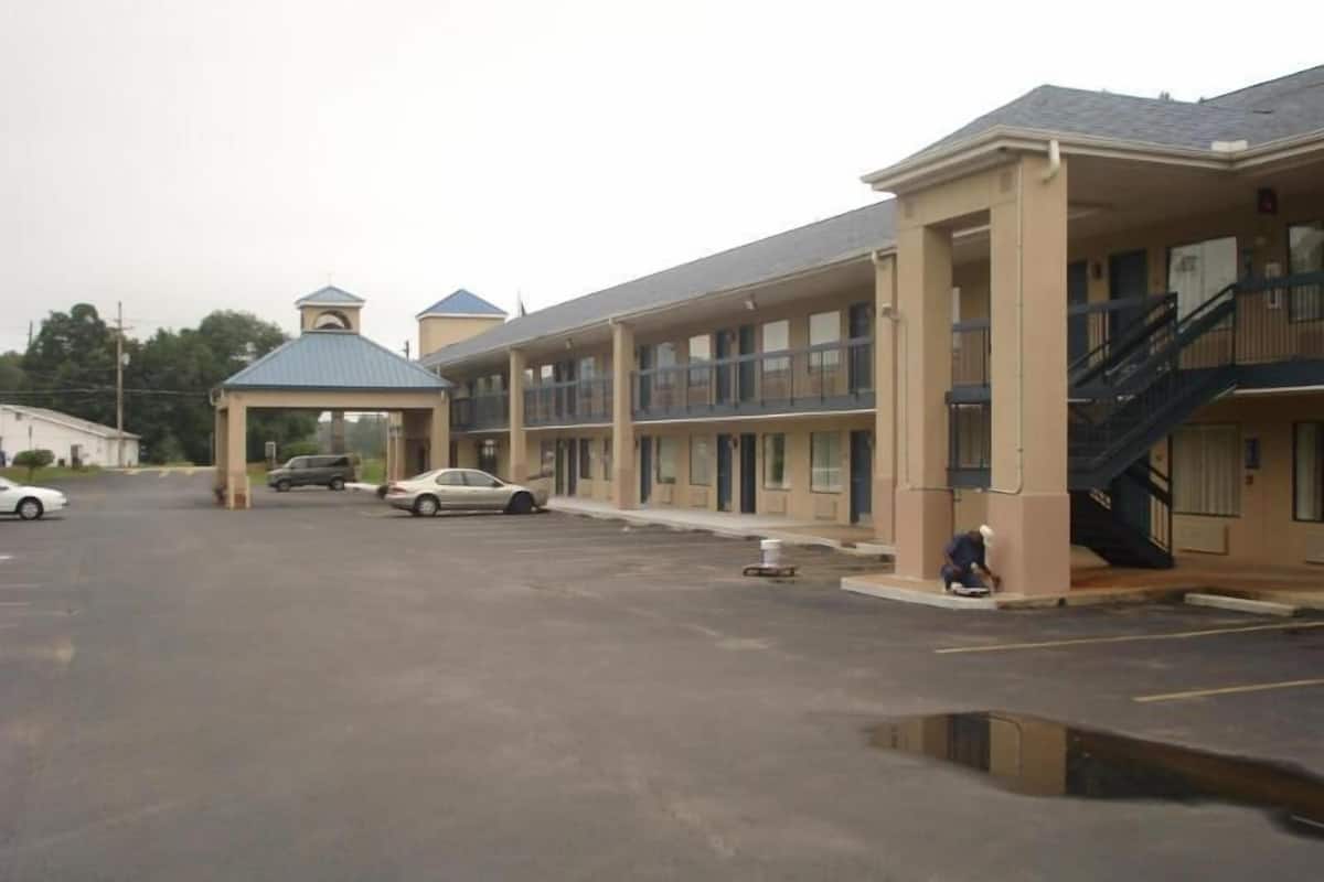 A motel with a covered parking area, multiple-story buildings, and a visible staircase.
