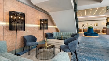 A modern lobby with seating arrangements, a reception desk, and a decorative wall.