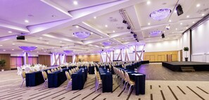 A large conference room with rows of tables and chairs, a stage, and a modern ceiling design. - Radisson Blu Hotel & Conference Centre, Salzburg (Salzburg)