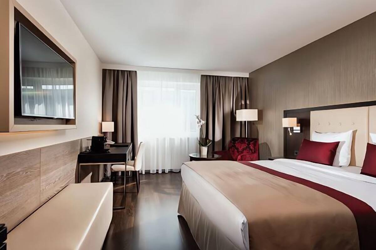 Ein Hotelzimmer mit Bett, Schreibtisch, Stuhl und Fernseher.
