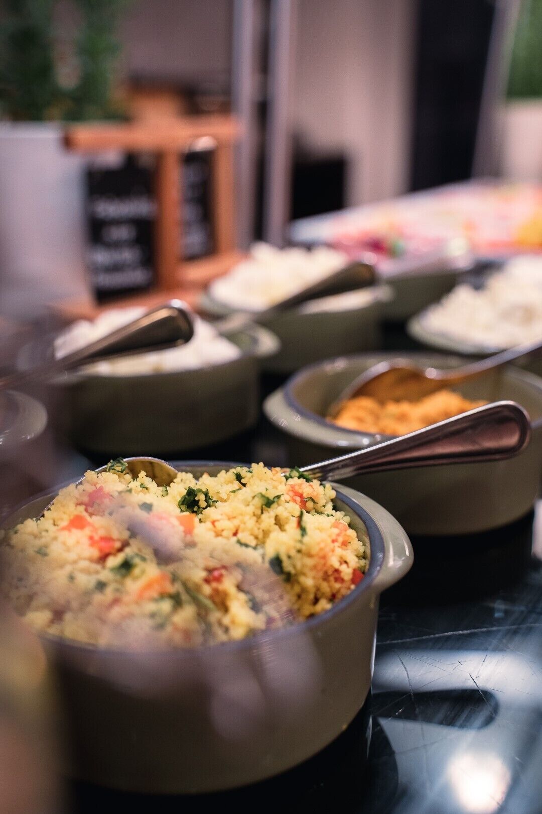 Un bufé con diversos platos, incluyendo un arroz con verduras y una crema.