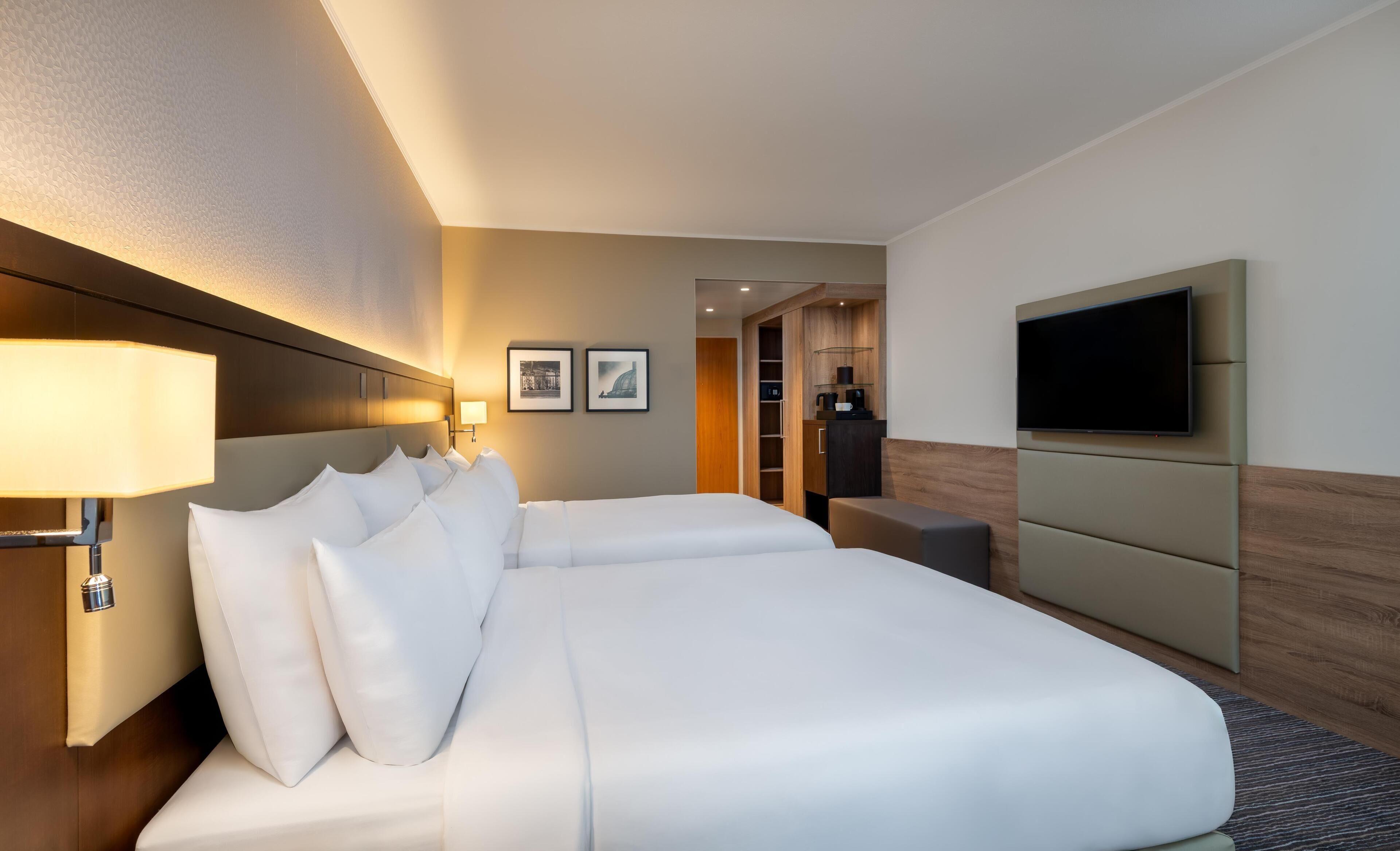 Una habitación de hotel con una cama grande, televisión de pantalla plana, escritorio y armario.