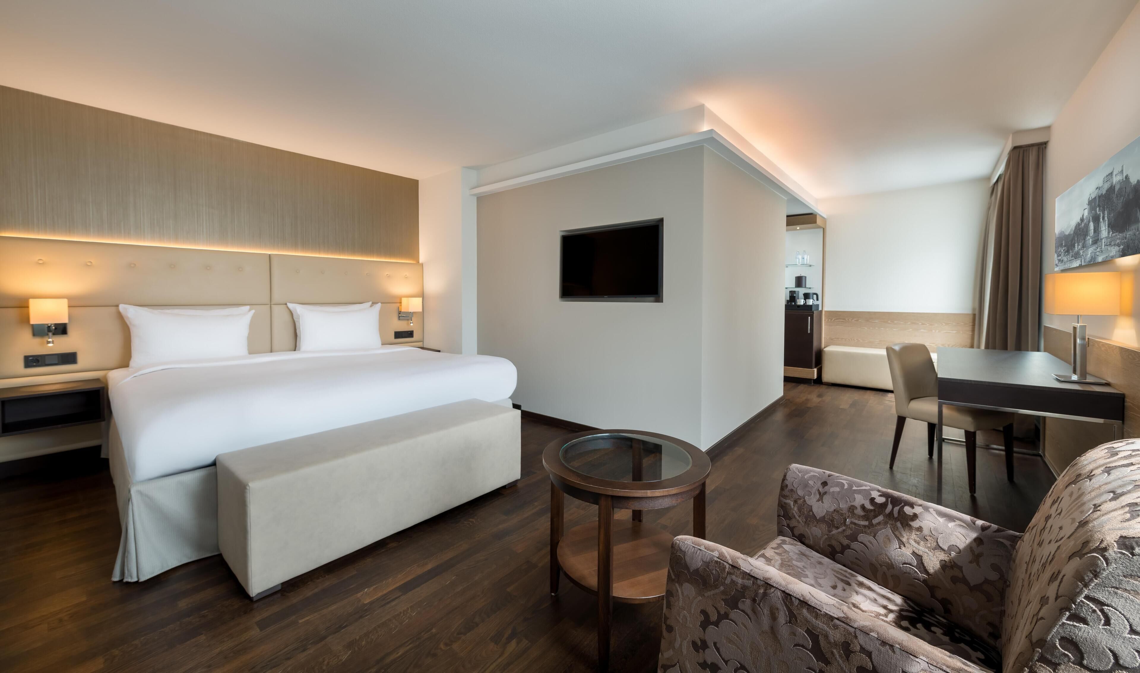 Ein Hotelzimmer mit Bett, Nachttischen, Schreibtisch, Stuhl und Fernseher.