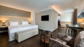 A hotel room with a bed, bedside tables, a desk, a chair, and a TV.