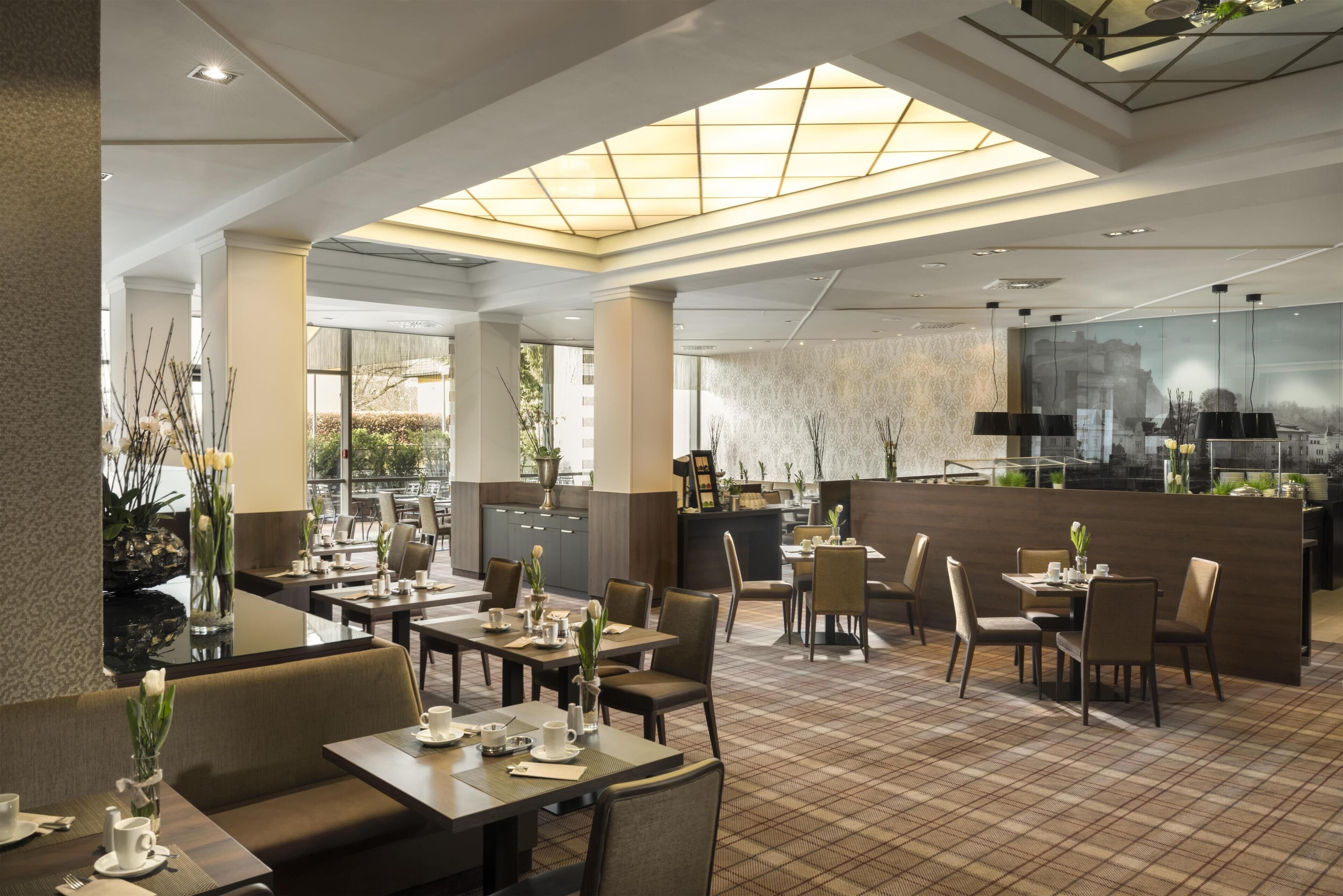 A modern restaurant with a high ceiling, large windows, and a central bar area.