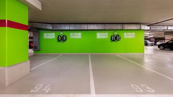 Ett parkeringsgarage med gröna väggar, ett stort antal parkeringsplatser och laddstationer för elfordon.
