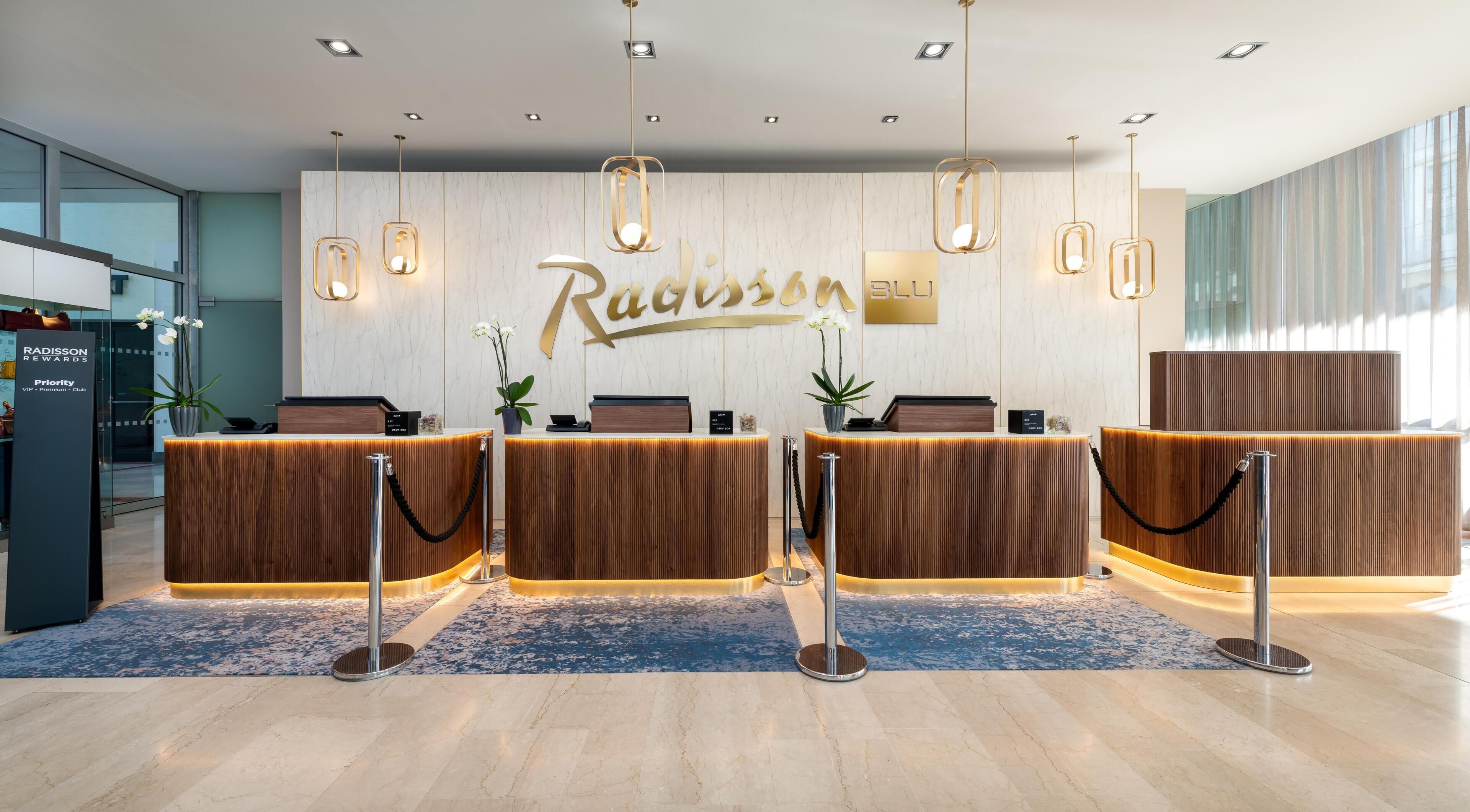 Un área de recepción con una pared de mármol, un mostrador de recepción y un letrero que dice 'Radisson'.