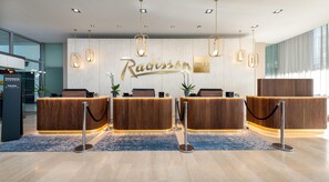 A reception area with a marble wall, a reception desk, and a sign that reads 'Radisson'.