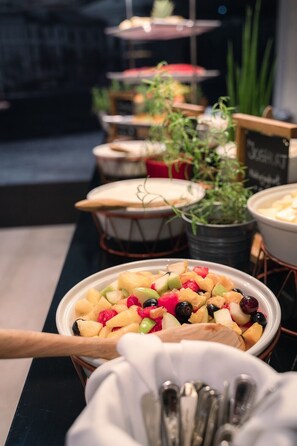 A buffet with a variety of fruits and vegetables, including apples, grapes, and carrots.