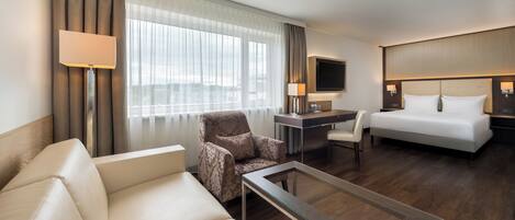 Una habitación de hotel con cama, sofá, escritorio y silla.