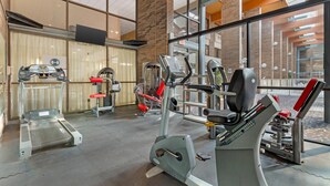A gym with cardio machines, weight machines, and a mirrored wall. - Clarion Hotel & Conference Center Lansing West (Lansing)