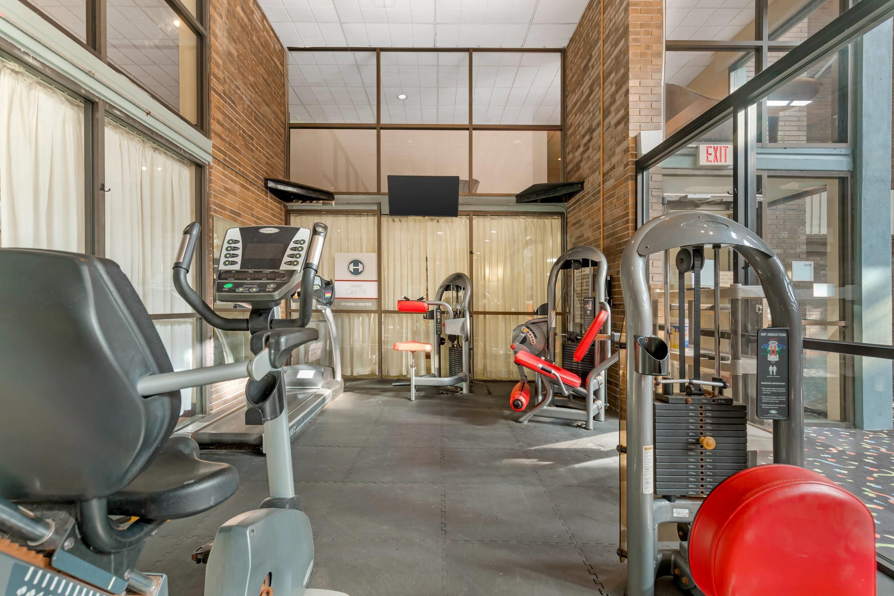 A gym with cardio machines, weightlifting equipment, and a mirrored wall.