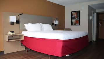 A hotel room with a bed, bedside tables, a wall-mounted lamp, and a door.