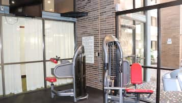 A gym with exercise equipment, a caution sign, and a view of the outside through large windows.