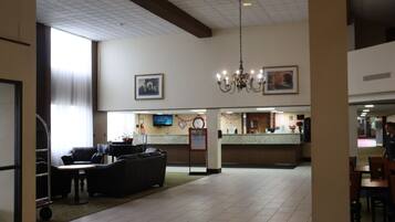 A hotel lobby with a reception desk, seating area, and a chandelier.