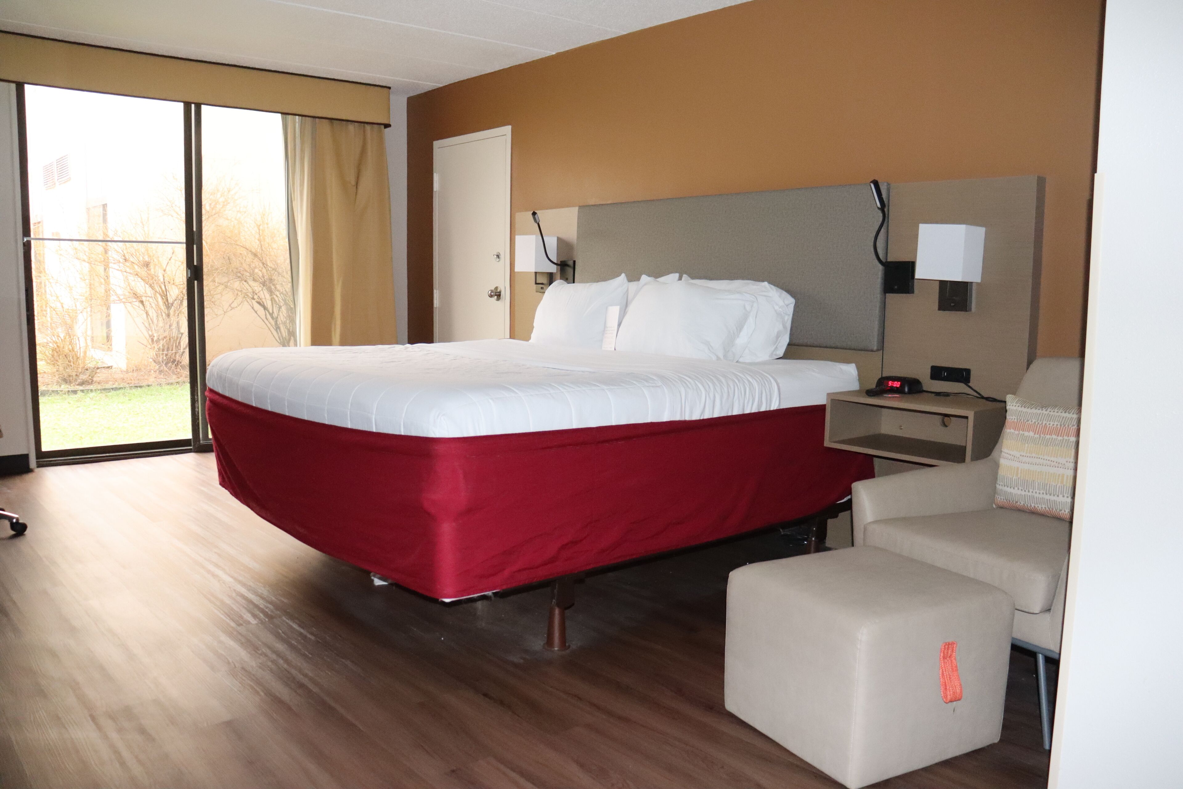 Quarto de hotel com uma cama grande, uma escrivaninha, uma cadeira e vista para o exterior.
