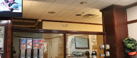 A breakfast bar with a coffee machine, a TV screen, and a window with a view of the outside.