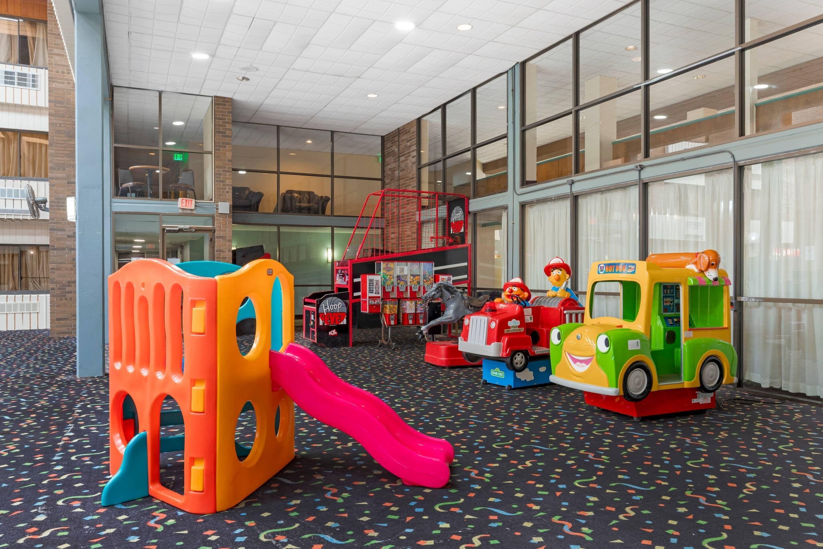 Zona de juegos infantiles con estructuras coloridas, que incluyen un tobogán y vehículos de juguete.