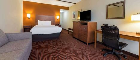A hotel room with a bed, a desk, a chair, a television, and a mirror.