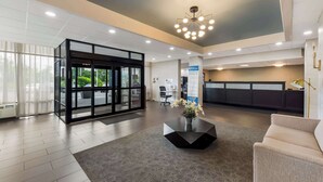 A modern lobby with a reception desk, a seating area, and a glass door entrance. - Best Western Executive Hotel Of New Haven - West Haven (West Haven)