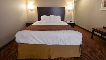 A hotel room with a large bed, two bedside tables, a nightstand, and a chair.