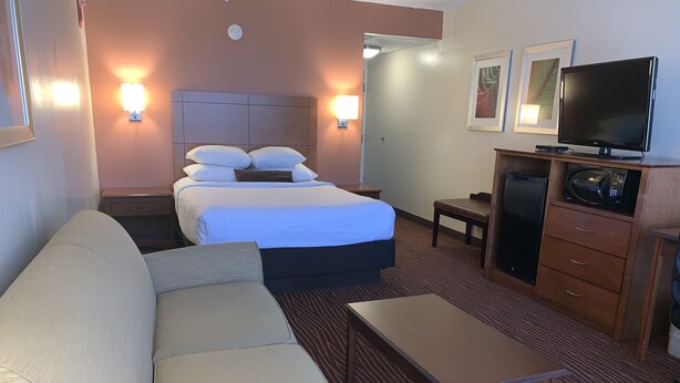 A hotel room with a bed, a sofa, a desk, a television, and a microwave. - Best Western Executive Hotel Of New Haven - West Haven (West Haven)