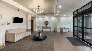 A modern hotel lobby with a sofa, coffee table, and a chandelier. - Best Western Executive Hotel Of New Haven - West Haven (West Haven)